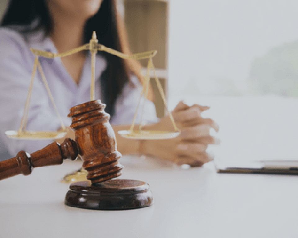 a wooden gavel resting on a table with gold scales of justice in the background